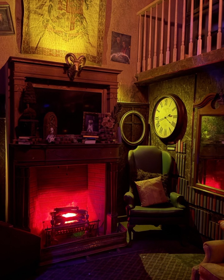A Victorian parlour: fire burning red in the grate, a grandfather clock, a green armchair